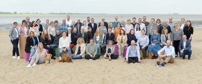 Viele Menschen sitzen und stehen im Sand | © Antje Schimanke