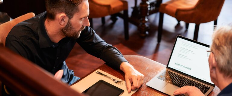 Zwei Männer schauen sich ein Bild auf dem Laptop an | © Sigrun Stangmann