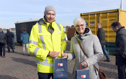 Mann und Frau lächeln in die Kamera und halten Tüten in der Hand | © BIS/Scheer