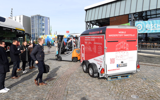 Anhänger steht mit Gabelstapler auf einem Markplatz vor Gebäuden | © BIS/Scheer