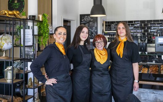 Vier Frauen halten sich in den Armen und lächeln in die Kamera. | © Wolfgang Heumer